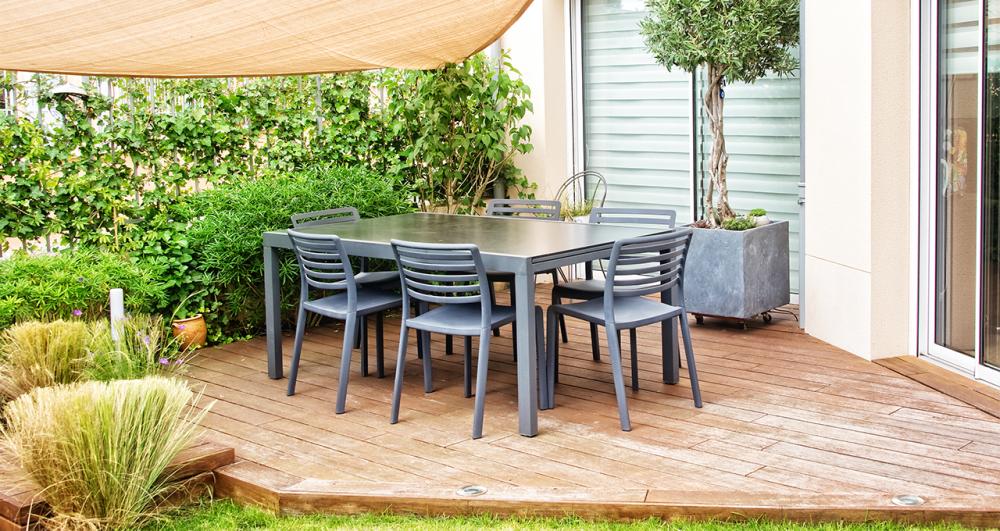 a cute corner deck surrounded by shrubs and concealed with a garden sail