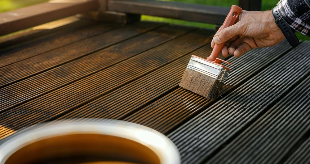 a homeowner refreshing a timber deck with a new lick of paint