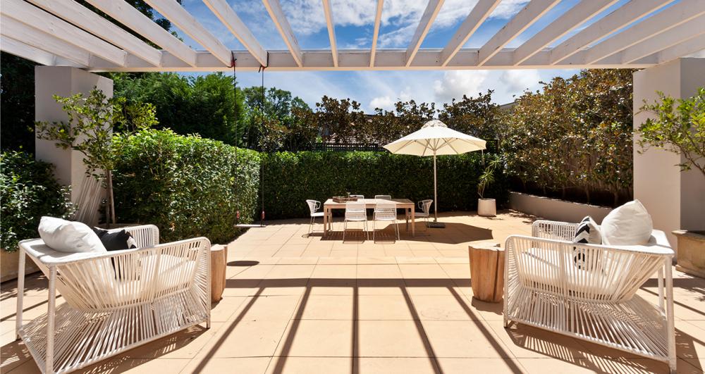 a luxurious garden covered by a pergola and surrounded by greenery