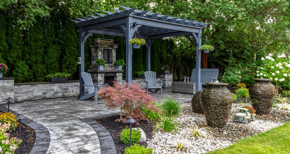 a stone patio in a beautiful garden seating area with a pergola