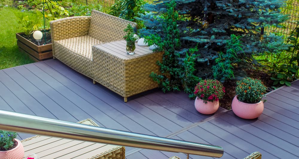 Low-maintenance composite decking installed in a landscaped garden, creating a durable outdoor seating area with garden furniture and decorative planting.