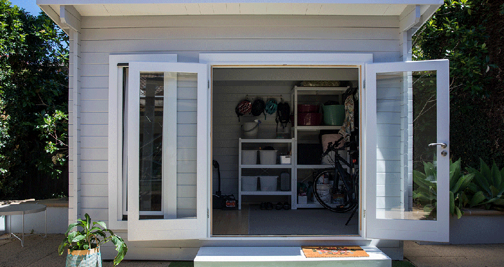 A grey garden shed with boxes and wall hangings to organise items with.