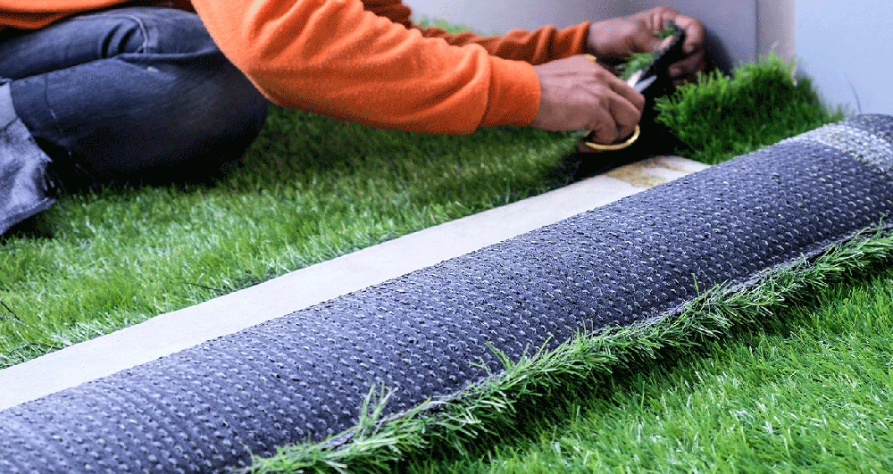 A closeup of a man installing an artificial lawn.