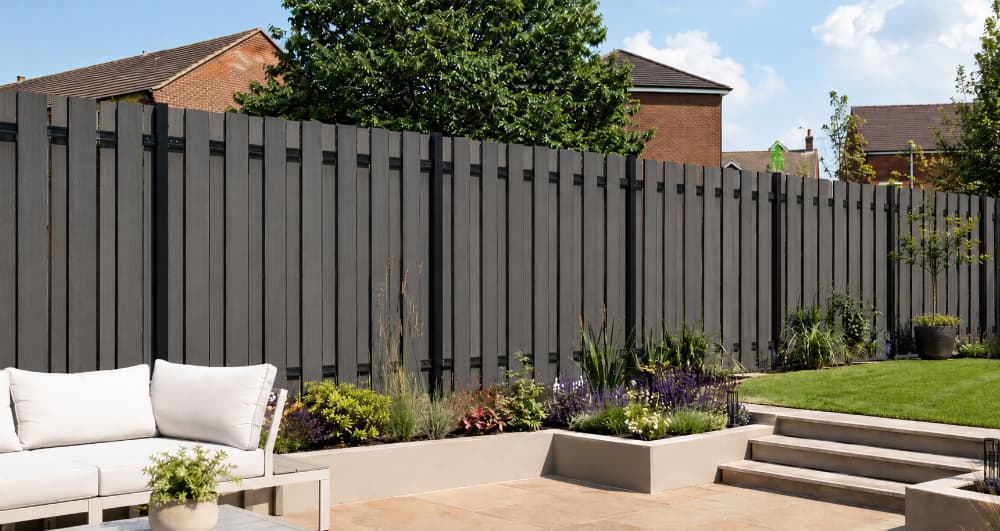 Modern landscaped garden featuring premium charcoal grey vertical slat composite fencing, raised planting beds, paved patio and lawn, creating a stylish, low-maintenance boundary with a contemporary architectural look.
