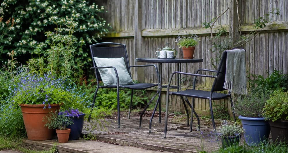 Simple garden seating area with outdoor chairs, table and potted plants