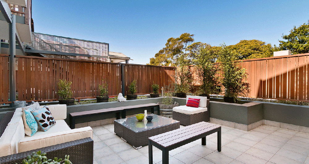 A patio seating area with a wooden slatted fence surrounding it.